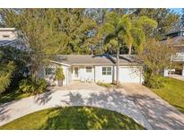 Inviting single-story home showcases a freshly graveled driveway, manicured lawn, and cozy seating area at 1908 Sutherland W Dr, Palm Harbor, FL 34683