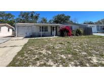 Modest single-story home with a front yard, driveway, and small covered porch at 7405 Country Club Dr, Hudson, FL 34667