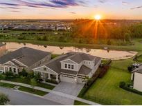 Stunning aerial view of home with pond, lush landscaping, and a beautiful sunset at 7415 Paradiso Dr, Apollo Beach, FL 33572