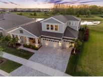 Stunning two-story home with a three-car garage, manicured lawn and a pond view at sunset at 7415 Paradiso Dr, Apollo Beach, FL 33572