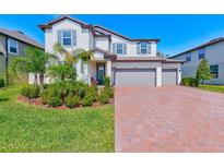 Charming two-story home featuring a three-car garage, manicured lawn, and beautiful landscaping at 11086 Sundrift Dr, Tampa, FL 33647