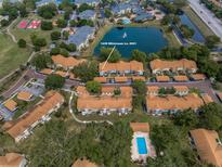 Beautiful aerial view of a condo community with mature landscaping, pool, and access to pond at 1438 Millstream Ln # 201, Dunedin, FL 34698