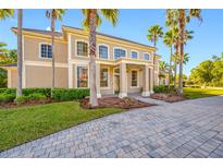 Impressive front exterior with a brick driveway, manicured lawn and mature palm trees at 19005 Cour Ests, Lutz, FL 33558