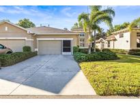 Charming single-story home with a well-maintained lawn and beautiful landscaping, including mature palm trees at 1922 Sifield Greens Way # 47, Sun City Center, FL 33573