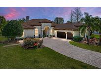Elegant home exterior featuring lush landscaping, brick driveway, and a neutral color palette at 34201 Kentucky Derby Pl, Dade City, FL 33525