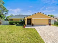 Charming single-story home featuring a brick driveway, manicured lawn and decorative landscaping, on a sunny day at 5117 Brynn Mawr Dr, Tampa, FL 33624