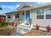 Charming home featuring a bright blue front door, gray siding, and manicured landscaping for great curb appeal at 5261 43Rd N Ave, St Petersburg, FL 33709