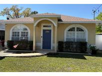 Charming single-story home with a well-manicured lawn, arched entryway, and shuttered windows at 6920 N Hubert Ave, Tampa, FL 33614