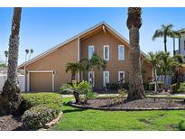 A striking two-story home featuring a well-manicured lawn, mature palms, and a two-car garage at 1101 Bay Pine Blvd, Indian Rocks Beach, FL 33785