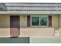 Home exterior featuring a neutral color scheme with a light gray roof and a front door on the left at 1801 Bedford Ter # 221, Sun City Center, FL 33573