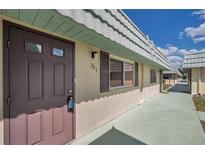 Street-side view of condo showcasing charming exterior, light-colored stucco walls, and welcoming front door at 1801 Bedford Ter # 221, Sun City Center, FL 33573