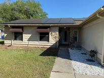 Single story home features solar panels, awning covered windows, and a well manicured yard at 520 Oak Creek Dr, Brandon, FL 33511