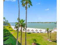 Beautiful view of the white sand beach with tiki hut umbrellas and calm water at 5701 Bahia Del Mar Cir # 408, St Petersburg, FL 33715