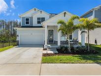 Charming two-story home featuring a well-manicured lawn, two-car garage, and inviting front porch with palm trees at 1439 Gopher Loop, Tarpon Springs, FL 34689