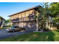 Two-story home with a balcony and three garage spaces, alongside an elegant gold convertible parked in the driveway at 2934 Lichen Ln # D, Clearwater, FL 33760