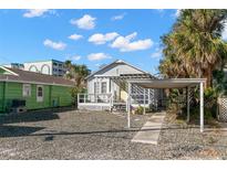 Charming single-story home featuring a welcoming porch, a carport, and tropical landscaping at 12404 Sunshine Ln, Treasure Island, FL 33706