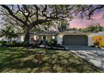 Charming single story home with a large tree, landscaped yard and an attached two car garage at 1887 Oak Forest E Dr, Clearwater, FL 33759