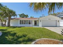 Charming single-story home featuring a well-manicured lawn, a white exterior, and tropical landscaping at 2650 E Vina Del Mar Blvd, St Pete Beach, FL 33706