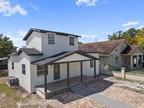 Charming two-story home with a covered front porch and a beautifully paved driveway under a partly cloudy sky at 2930 W Arch St, Tampa, FL 33607