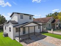 Inviting two-story home with a covered front porch and a beautifully paved driveway and well maintained lawn at 2930 W Arch St, Tampa, FL 33607