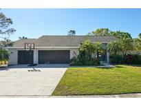Charming single-story home with a well-maintained lawn, mature landscaping, and a spacious driveway leading to a two-car garage at 3994 Belmoor Dr, Palm Harbor, FL 34685