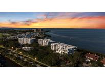 Stunning aerial view of waterfront condos with lush landscaping, marina, and vibrant sunset skies at 2410 Harbourside Dr # 142, Longboat Key, FL 34228