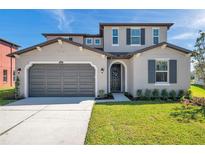 Charming two-story home featuring a gray exterior, well-manicured lawn, and a gray two car garage at 28935 Lucero Ln, Wesley Chapel, FL 33543