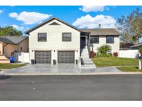Charming two-story home featuring a modern gray driveway, two-car garage, and well-manicured lawn at 4954 Cardinal Trl, Palm Harbor, FL 34683
