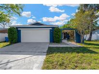 Charming single-story home featuring a two-car garage and well-manicured landscaping, painted in a serene blue hue at 6208 Imperial Ky, Tampa, FL 33615
