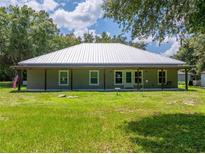 Ranch-style home with a metal roof and a charming covered porch overlooking a lush green lawn at 9017 S County Line Rd, Lithia, FL 33547