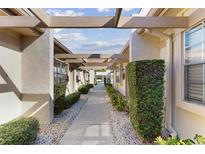 Landscaped walkway featuring lush greenery and a decorative pergola, adding curb appeal at 11135 Carriage Hill Dr # 5, Port Richey, FL 34668