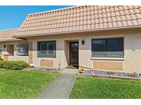 Inviting front exterior with a tiled roof, landscaping, and charming walkway leading to the front door at 19029 Us Highway 19 N # 27E, Clearwater, FL 33764