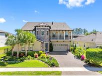Two-story home featuring a brick driveway, manicured lawn, mature palm trees, and stone accents on the facade at 19412 Lonesome Pine Dr, Land O Lakes, FL 34638