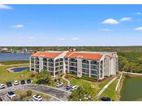 Beautiful condo building with a red tile roof and lovely landscaping, near a pond and parking area at 234 Mariner Dr # 234, Tarpon Springs, FL 34689