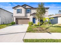 Charming two-story home featuring a two-car garage, well-maintained lawn, and a welcoming blue front door at 36365 Flats St, Zephyrhills, FL 33541