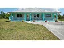 Charming turquoise home with white trim, metal roof, and a cozy front porch at 6418 Austrian Blvd, Punta Gorda, FL 33982