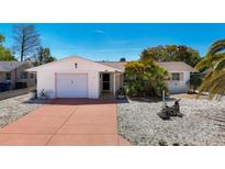 Charming single-story home featuring a brick exterior, mature landscaping, and a one-car garage at 7330 Cherry Laurel Dr, Port Richey, FL 34668