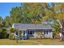 Charming single-story home featuring a yellow door, manicured lawn and mature trees at 145 38Th Ne Ave, St Petersburg, FL 33704