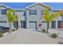 Beautiful townhome showcasing a two-story exterior, grey paint, shuttered windows, and a two-car garage at 1504 Colt Creek Pl, Wesley Chapel, FL 33543