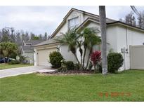 Charming home featuring a well-manicured lawn, mature palms and decorative landscaping at 30829 Iverson Dr, Wesley Chapel, FL 33543