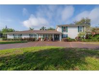 Charming two-story home with white brick, green shutters, and a spacious brick driveway at 7922 Spring Valley Dr, Tampa, FL 33615