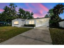 Charming single-story home with a spacious driveway and carport offers curb appeal at dusk at 8003 W Powhatan Ave, Tampa, FL 33615