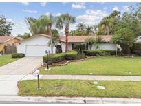 Charming single-story home featuring a well-manicured lawn, mature landscaping, and a classic red tile roof at 1870 Wateroak W Dr, Clearwater, FL 33764