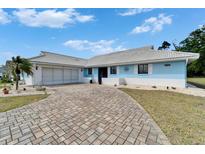 Charming blue single-story home with a brick driveway and well-maintained landscaping at 1929 New Bedford Dr, Sun City Center, FL 33573