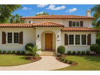 Inviting two-story home featuring a red tile roof, arched entryway, and manicured lawn with tasteful landscaping at 2217 Brevard Ne Rd, St Petersburg, FL 33704