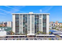 High-rise building with multiple balconies and a parking lot, set against a blue sky at 400 Island Way # 1708, Clearwater Beach, FL 33767
