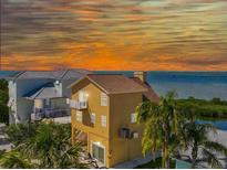 Charming multi-story home with a balcony, palm trees, and a picturesque waterfront view at sunset at 6633 Driftwood Dr, Hudson, FL 34667