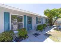Charming home featuring a light-gray brick exterior with striking blue shutters and a beautifully landscaped front yard at 6712 W Clifton St, Tampa, FL 33634
