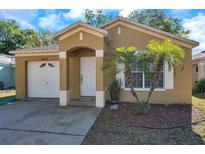 Charming single-story home with tan stucco, an arched doorway, and neat landscaping in a sunny setting at 8528 Quarter Horse Dr, Riverview, FL 33578