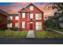 Charming red two-story townhome with manicured lawn and beautiful sunset, creating a warm and inviting ambiance at 9118 Lake Chase Island Way # 9118, Tampa, FL 33626